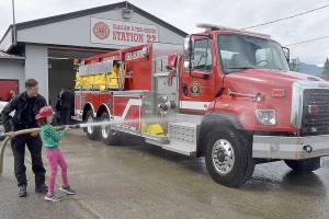 Abby Counts, 8, with assistance from her father, Taylor Counts, an EMT with Clallam 2 Fire-Rescue, gives a newly acquired tender truck a ceremonial wash down during a push-in ceremony on Saturday at the districts Station 22. The truck, tender 22, cost $459,439 and was paid for by the fire districts 2020 levy lid lift. Saturdays ceremony also included a blessing by the Lower Elwha Klallam Tribe and a push-in of the truck into its berth. The tender replaces a 31-year-old truck that had reached the end of its useful life. (Keith Thorpe/Peninsula Daily News)