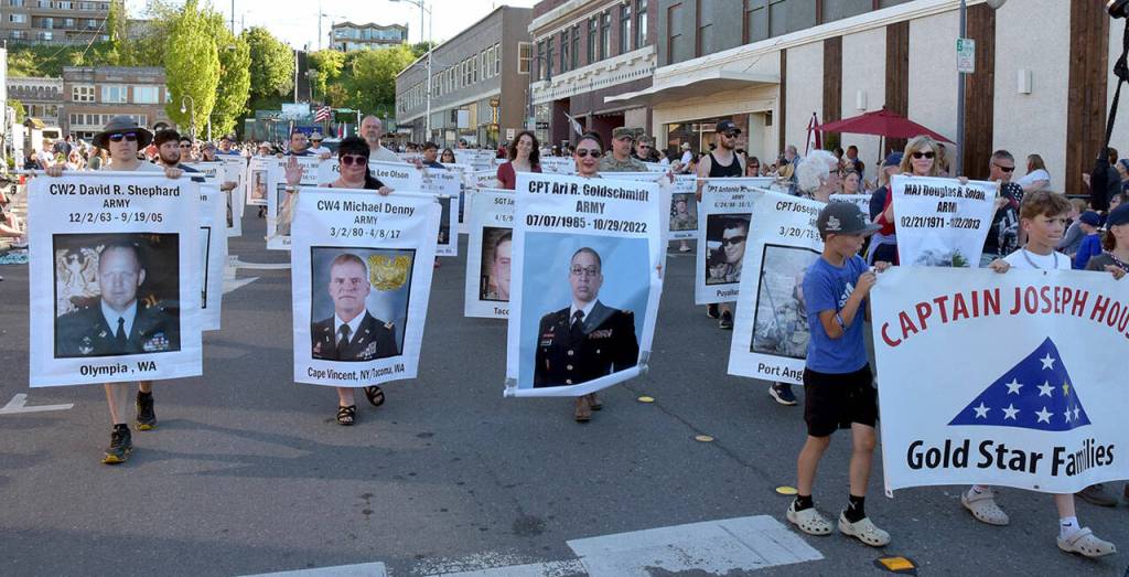 Members of the Captain Joseph House parade entry carry photos of deceased military personnel during Thursdays Independence Day parade. (Keith Thorpe/Peninsula Daily News)