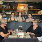 Andrea Raymor, left, and Christine Cray, former owners of the Spruce Goose Cafe on Airport Road in Port Townsend, share a moment with the new owners of the cafe in the background, Ashley Owen, left, Vanessa McKenney, middle, and sister Kathryn McKenney during a break between cooking and waitressing. (Steve Mullensky/for Peninsula Daily News)