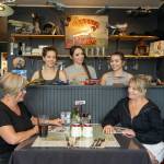 Andrea Raymor, left, and Christine Cray, former owners of the Spruce Goose Cafe on Airport Road in Port Townsend, share a moment with the new owners of the cafe in the background, Ashley Owen, left, Vanessa McKenney, middle, and sister Kathryn McKenney during a break between cooking and waitressing. (Steve Mullensky/for Peninsula Daily News)