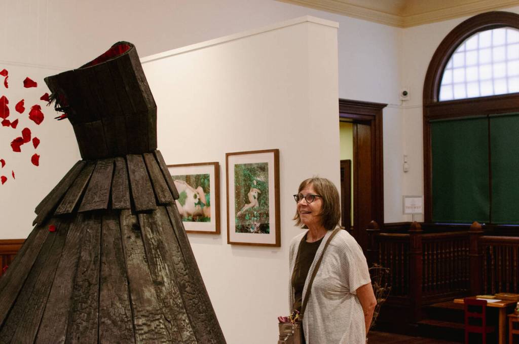 Terri Mack takes in Jeanne K Simmons burnt cedar sculpture, Grief Monument for Corbin on July 11. (Elijah Sussman/Peninsula Daily News)