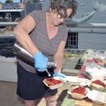 Port Angeles Farmers Market board member Vanessa Barrington adds whipped cream to a strawberry shortcake being sold at the market on Saturday as a fundraiser for market operations. Proceeds from shortcake sales help pay for insurance, organization memberships, rental fees, printing, postage and payroll for market staff. (Keith Thorpe/Peninsula Daily News)