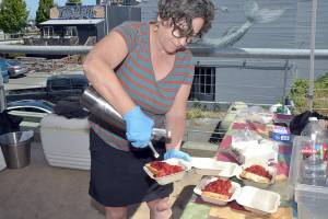 Port Angeles Farmers Market board member Vanessa Barrington adds whipped cream to a strawberry shortcake being sold at the market on Saturday as a fundraiser for market operations. Proceeds from shortcake sales help pay for insurance, organization memberships, rental fees, printing, postage and payroll for market staff. (Keith Thorpe/Peninsula Daily News)
