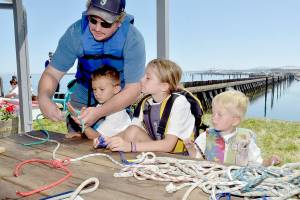 Brian Hoffman of Port Angeles, left, assists his children, from left, Clayton Hoffman, 6, Lacey Hoffman, 8, and Rhett Hoffman, 3, during a knot-tying workshop at the Port Angeles Yacht Club, one of numerous venues for Saturdays Day of Play. (Keith Thorpe/Peninsula Daily News)