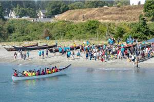 A canoe from the Scianew Tribe, from Beecher Bay on Vancouver Island, approaches the beach and asks permission to land from a Jamestown SKlallam tribal member on the beach. The annual Intertribal Canoe Journey, this year also known as the Power Paddle to Puyallup Youth Canoe Journey, landed 13 canoes from around the Olympic Peninsula and Canada on the beach at Fort Worden on Friday. The Jamestown SKlallam Tribe is the host tribe for the landings in Port Townsend. (Steve Mullensky/for Peninsula Daily News)