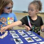 Riley Lohman, left, and Arya Davis, both 6, of Port Angeles, play a matching game of sea life at an activity table setup by the Olympic Coast National Marine Sanctuary during a 30th birthday party for the sanctuary at Waterfront Park. The celebration included information and activity booths from a variety of environmental stewardship groups, including the Feiro Marine Life Center, which will soon share a building at the location with the marine sanctuary. (Keith Thorpe/Peninsula Daily News)