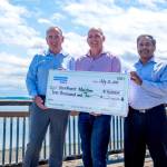 From left, Gregg Madden, Jake Beattie and Gopal Nair hold a check donation from DNV to Northwest Maritime at the Northwest Maritime campus in Port Townsend. (Northwest Maritime)