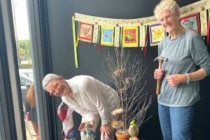 Debra E. Olson, left, and Leslie Dickinson install Birds of a Feather in the Fiber Habit walk-by exhibit of Peninsula Fiber Artists, 675 Tyler St. in Uptown Port Townsend.