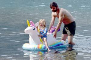 Maya Jennings-Kelly, 5, of Port Angeles gets a push from Nick Simpson of Port Angeles during an outing to Bovees Meadow at Lake Crescent in Olympic National Park on Saturday. Warm weekend weather drew hundreds of people to the Barnes Point area of the lake, leading to full parking lots and busy beaches. (Keith Thorpe/Peninsula Daily News)