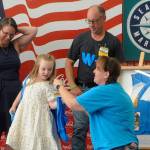 Jessica Davis helps Jordyn Mancuso-Staus put on a personalized vest during a ribbon cutting for the remodel of the Sequim Walmart as Jordyn's grandmother Donna Staus, left, and Jessica's husband John-Paul Davis watch. The Davises presented Donna with a shadowbox with her late-husband Lynie Staus' work vest. He died May 1 shortly before his 24th anniversary with the company. (Matthew Nash/Olympic Peninsula News Group)