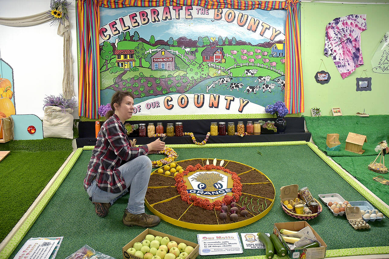 Erin Moilanen of the Crescent Grange arranges the groups display in preparation for the Clallam County Fair on Tuesday in Port Angeles. (Keith Thorpe/Peninsula Daily News)