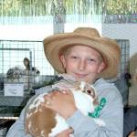 Gage Erickson poses with his rabbit in the rabbit barn at the Clallam County Fair on Friday. (Dave Logan/ For Peninsula Daily News)