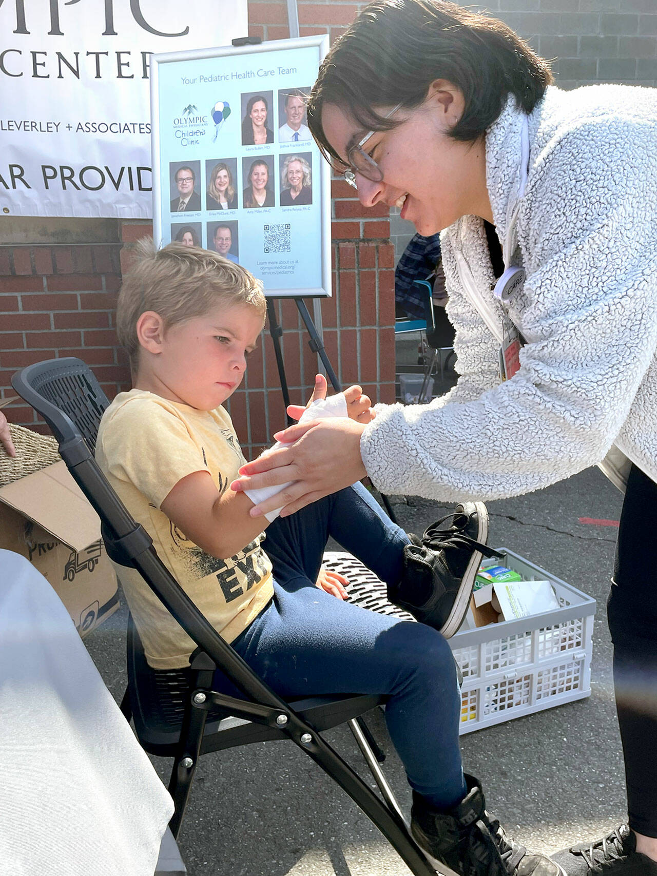 Atreyu Jones, 5, watches at Daisy Acedvado of Olympic Medica Center puts a fake cast on his arm at the Port Angeles School Districts 16th back to school fair for families and students on Saturday at Jefferson Elementary. Free haircuts, backpacks filled with school supplies and clothing were available for students, and health and community resource information was provided for parents. (Paula Hunt/Peninsula Daily News)