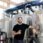 Levi Liberty enjoys one of his beers in front of Social Fabric Brewerys three fermenters in Port Townsend. (Elijah Sussman/Peninsula Daily News)