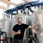 Levi Liberty enjoys one of his beers in front of Social Fabric Brewerys three fermenters in Port Townsend. (Elijah Sussman/Peninsula Daily News)
