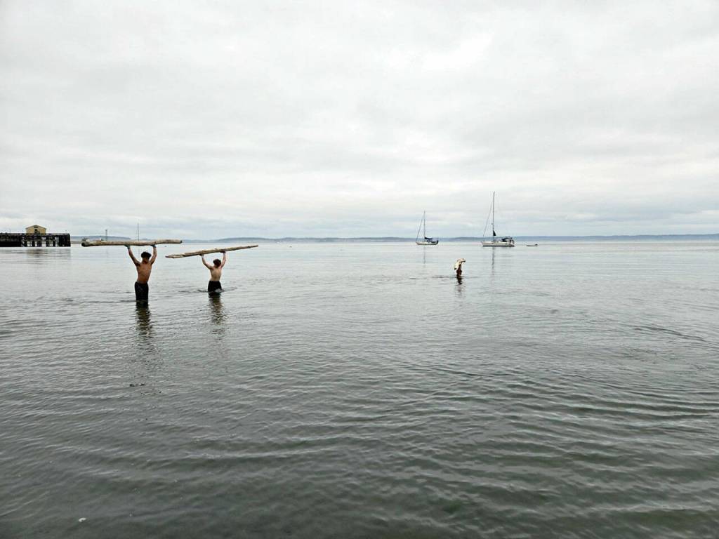 During an overhead static press lift and walk of a log, Port Townsend High School athletes Manaseh Lanphear Ramirez and Grady White both opted to challenge themselves above their knees, while Silas Klontz submerged himself beyond his armpits.