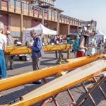 Wooden boat enthusiasts look over four classic Pocock-built sculls on display during the Wooden Boat Festival on Friday at Point Hudson Marina in Port Townsend. (Steve Mullensky/for Peninsula Daily News)