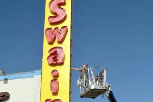 Seth Stewart of Silverdale-based Hanson Signs inspects the side panels on a new business sign at Swains General Store in Port Angeles on Thursday. Swains general manager Don Droz said the original iconic sign dated back to the 1960s and was in need being replaced. Droz said the neon-lit lettering from the old sign was preserved and incorporated into the new marquee. (Keith Thorpe/Peninsula Daily News)