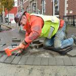 Ian Mason of Edgewood, an employee of Titan Earthworks, hammers a brick paver into place at the corner of First and Oak streets in downtown Port Angeles on Wednesday as part of a project to replace and repair sidewalks and curbs across the city. Included are the installation of improved wheelchair ramps, replacement of overgrown trees and numerous street corner repairs. (Keith Thorpe/Peninsula Daily News)