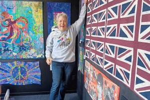 Port Angeles textile artist Merrie Jo Schroeder, installing the Beatlemania walk-by exhibit at 675 Tyler St., Port Townsend. The display of Beatles memorabilia and Beatles-themed art quilts and textile pieces will continue through November.