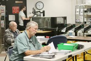 Ray Farrell, left, and Daniel Cain, center, prepare mail-in ballots for counting on Tuesday morning at the Clallam County courthouse in Port Angeles. The tabulating machine can be seen in the background with its operator. Election results, released after press time Tuesday, are online at cmg-northwest2.go-vip.net/peninsuladailynews. Full coverage will appear in Thursdays print edition. (Dave Logan/for Peninsula Daily News)