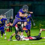 Steve Mullensky/for Peninsula Daily News
Quilcene's Mason Iverson leaps over his would-be Oakville Acorn tackler and runs for a first down in the first quarter of a Class 1B Quad District winner-to-state-game played under the lights on Friday in Port Townsend.