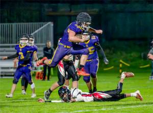 Steve Mullensky/for Peninsula Daily News
Quilcene's Mason Iverson leaps over his would-be Oakville Acorn tackler and runs for a first down in the first quarter of a Class 1B Quad District winner-to-state-game played under the lights on Friday in Port Townsend.