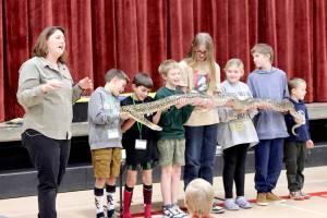 April Jackson, The Reptile Lady, speaks while students hold a 12-foot Burmese python named Mr. Pickles at Jefferson Elementary School in Port Angeles on Friday. The students, from left to right, are Braden Gray, Bennett Gray, Grayson Stern, Aubrey Whitaker, Cami Stern, Elliot Whitaker and Cole Gillilan. Jackson, a second-generation presenter, showed a variety of reptiles from turtles to iguanas. Her father, The Reptile Man, is Scott Peterson from Monroe, who started teaching about reptiles more than 35 years ago. (Dave Logan/for Peninsula Daily News)