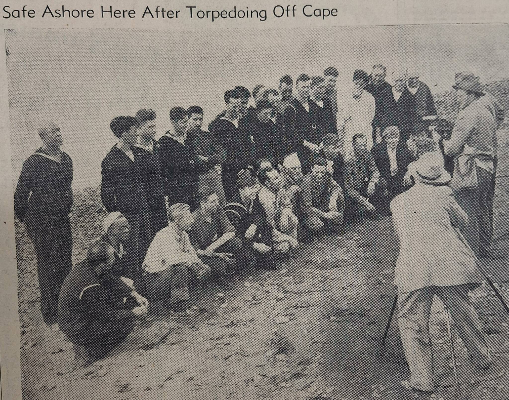 31 members of the crew on the beach in Port Angeles standing before news photographers. (submitted photo)