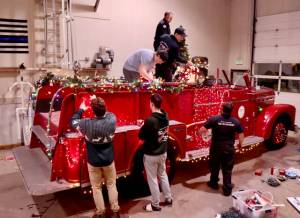 Santa’s elves, better known as the Port Angeles Fire Department, decorate their vintage 1956 Seagrave fire engine to get ready for the six-day Operation Candy Cane. This will be the 39th annual trek through the streets of Port Angeles to collect donations for area food banks. (Dave Logan/for Peninsula Daily News)