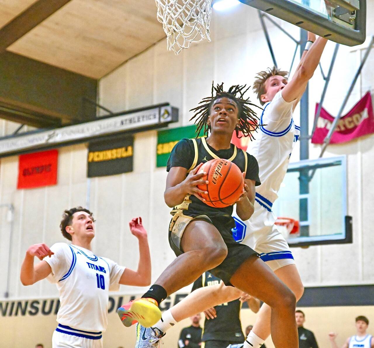 Peninsula Colleges Akeem Sulaiman drives to the hoop Saturday in Port Angeles against Silas Wright (10) and Ben Thornbrue of Lane.Sulaiman scored 20 to go with 12 rebounds. (Jay Cline/Peninsula College)