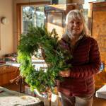 Ann Johnson of Lazy J Tree Farm and two other women make Christmas wreaths in a sunlit room of the Johnson home.