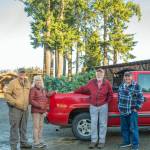 From right, Mark Silkas and Steve Sahnow receive a donated Noble fir from Ann and Steve Johnson at the Lazy J Tree Farm to be the Giving Tree sponsored by the Friends of Sequim outside of Habitat for Humanity, which is hung with personal care items and presents for passersby, who also are encouraged to leave behind a present. (Emily Matthiessen/Olympic Peninsula News Group)