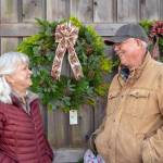Outside the Christmas Barn at Lazy J Tree Farm, Ann and Steve Johnson smile at each other in front of wreaths Ann prepares with two other women for the Christmas season. (Emily Matthiessen/Olympic Peninsula News Group)