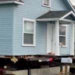 Striped legs with ruby slippers peek out from under a house being prepared to move from a lot on Third Street in Port Angeles. (Kelley Lane/Peninsula Daily News)