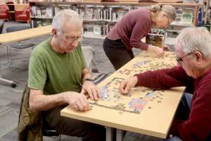 Tim Branham, left, his wife Mickey and Bill Pearl work on a 500-piece jigsaw puzzle entitled “Days to Remember.” The North Olympic Library at its main branch on South Peabody Street in Port Angeles sponsored a jigsaw puzzle contest on Saturday, and 15 contestants challenged their skills. With teams of two to four, contestants try to put together a puzzle in a two-hour time limit. Justin Senter and Rachel Cook finished their puzzle in 54 minutes to win the event. The record from past years is less than 40 minutes. The next puzzle contest will be at 10 a.m. Feb. 8. (Dave Logan/for Peninsula Daily News)