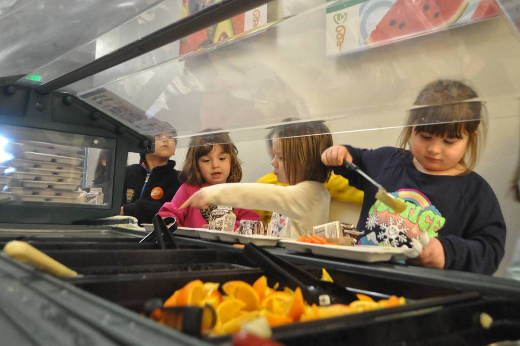 Kindergarteners Pria Barr, Kiara Englebright and Lilly Aslin gather their lunches before heading back to class, where all Greywolf Elementary students eat because they do not have a dedicated cafeteria. (Matthew Nash/Olympic Peninsula News Group)