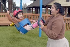 Madeline Jones of Forks gives a push to her daughter, Amelia Jones, 2, during a family outing at the Dream Playground at Erickson Playfield on Thursday in Port Angeles. They took advantage of a mild midwinter day while facing the prospect of colder conditions forecast for the coming week. (Keith Thorpe/Peninsula Daily News)