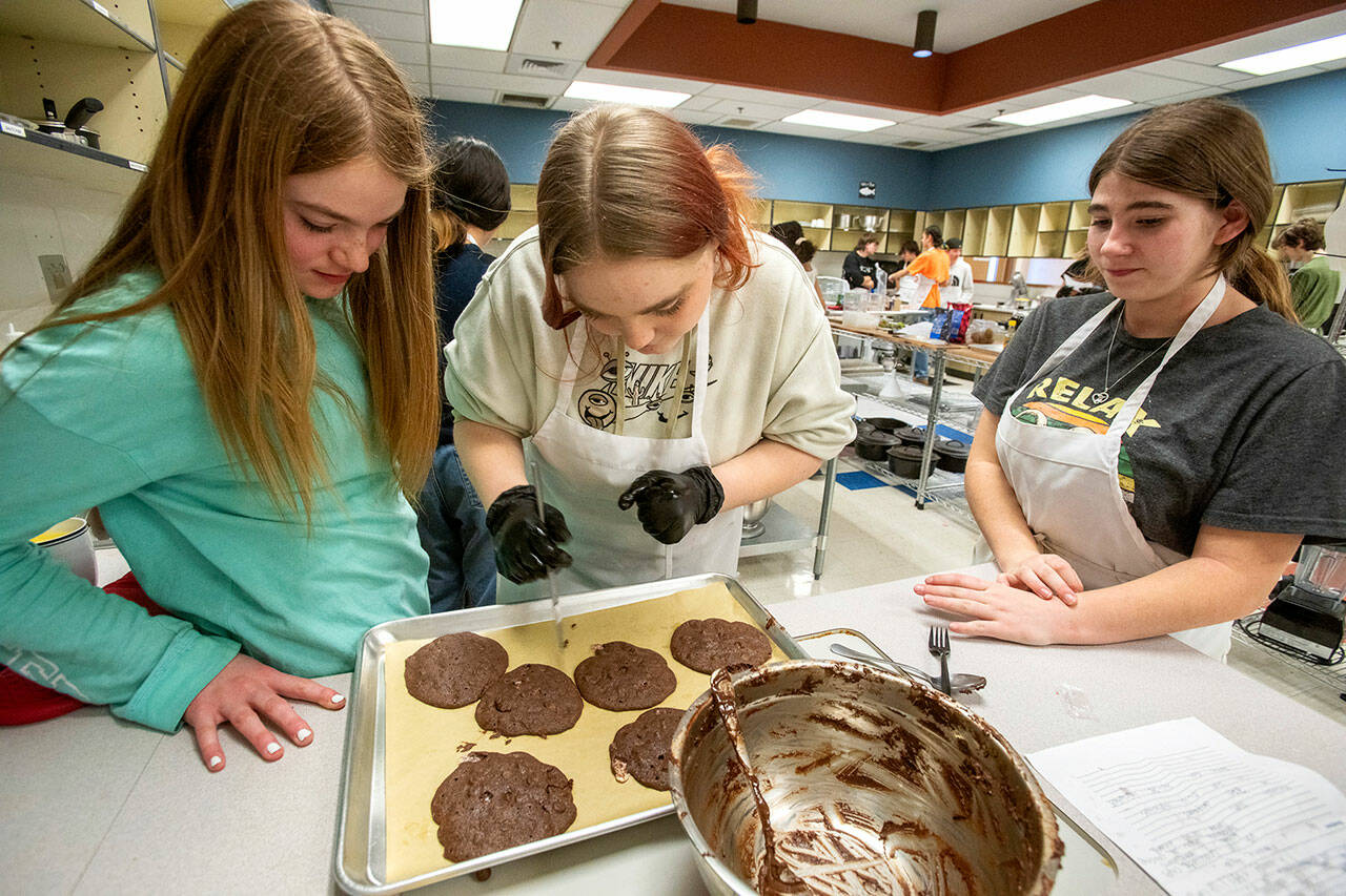 Fresh out of the oven, three students in the Chimacum High School culinary arts program separate cookies that were to be judged by a panel of experts during their final midterm exam on Tuesday. (Steve Mullensky/for Peninsula Daily News)