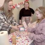 Madison Canterbury, 7, of Shelton looks at a Valentines gift she created with the assistance of volunteers Chandra McGuff, left, and Nicole Lemon at a craft table set up outside the Silver Lining Cafe at The Wharf on Saturday on the Port Angeles waterfront. Youngsters were given the opportunity to create gifts and Valentines cookies during the event. (Keith Thorpe/Peninsula Daily News)