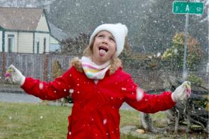 Lavender Cowder, 7, in her front yard on A street in west Port Angeles, tries to taste a snowflake during a brief snow shower Sunday. (Dave Logan/for Peninsula Daily News)