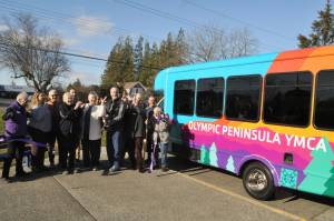 Mike Speer of Bonney Lake, the brother of Sherry Nagel, a former board member of the YMCA of the Olympic Peninsula, cuts a ceremonial ribbon on Jan. 28 courtesy of the Sequim-Dungeness Valley Chamber of Commerce to commemorate a new bus that Nagels estate helped fund. The bus is dedicated in Nagels honor. (Matthew Nash/Olympic Peninsula News Group)