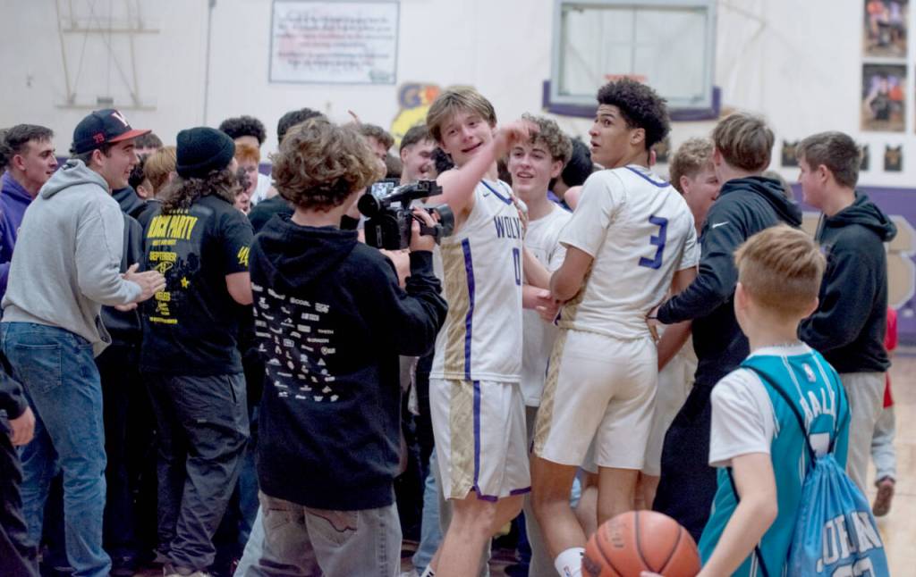 Sequim students storm the court and celebreate with Ethan Melnick (0) and Solomon Sheppard (3) after the Wolves beat Bremerton 66-61 on Monday night to earn a share of the Olympic League boys basketball championship. Sequim and Bremerton will play in Poulsbo tonight in a rubber match to determine playoff seeding. (Emily Mathiessen/Olympic Peninsula News Group)