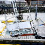 A yellow oil-containment boom surrounds the 60-foot power cruiser Goldfinch after it sank at the Point Hudson Marina on Saturday. The boat was on its way from Seattle to Anacortes when it started taking on water. It made it to the Point Hudson and struck the breakwater as it entered the harbor but was able to be steered into slip 3, where it immediately sank. Port of Port Townsend staff responded and deployed the hard boom and absorbent material to contain the fuel spill. As of Monday afternoon, about 1,000 gallons of diesel had been recovered by Global Diving and Salvage with 650 gallons from the fuel tanks of the Goldfinch and the remainder being sopped up by absorbent material. The U.S. Coast Guard and the state Department of Ecology responded and performed additional containment. A plan for recovery was in the works, but it wasnt expected to begin before Wednesday due to weather. (Steve Mullensky/for Peninsula Daily News)