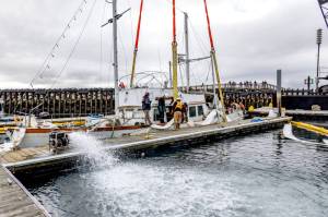 Workers from Global Diving and Salvage of Seattle pump water on Monday from inside the hull of the 50-foot powerboat Goldfinch that sank in Point Hudson Marina on Feb. 22. The boat was later towed to Port Townsend Marina. (Steve Mullensky/for Peninsula Daily News)