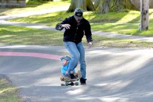 Lucas Niclas, 23 months, hangs onto to the leg of his father, Ben Niclas of Sequim, as they make their way around the pump track on Friday at Erickson Playfield in Port Angeles. The pair were on a family outing to the popular attraction. (Keith Thorpe/Peninsula Daily News)