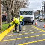 Workers from Jefferson Transit repaint the bus stop parking area at the corner of Madison and Jefferson streets in Port Townsend on Friday. The yellow paint was purchased from a local hardware store. (Steve Mullensky/for Peninsula Daily News)