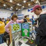 Cindy Taylor of Port Townsend, representing the environmental group Local 20/20, points to printed information available about the organization to an interested party while at the Jefferson County Connectivity Summit at Chimacum High School on Saturday. (Steve Mullensky/for Peninsula Daily News)