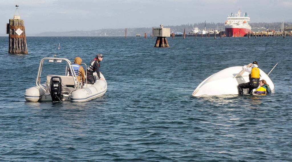 Liam Wiedenhoeft leans out of a chase boat piloted by sailing coach Eric Lesch after sailing students Andrew Corson and Ben Davids capsized their boat in stiff winds in Port Angeles Harbor. (Keith Thorpe/Peninsula Daily News)