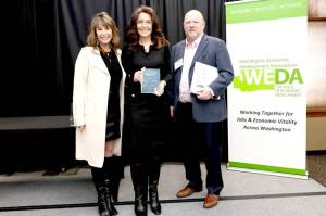 Clallam County Economic Development Council Director of Operations Lorie Fazio, left, and Executive Director Colleen McAleer stand with Michael Cade, executive director of Thurston EDC who presented the WEDAs 2025 Innovation in Economic Development award. The EDC received the award last month in recognition of its Clallam Forest Product Innovation Program.